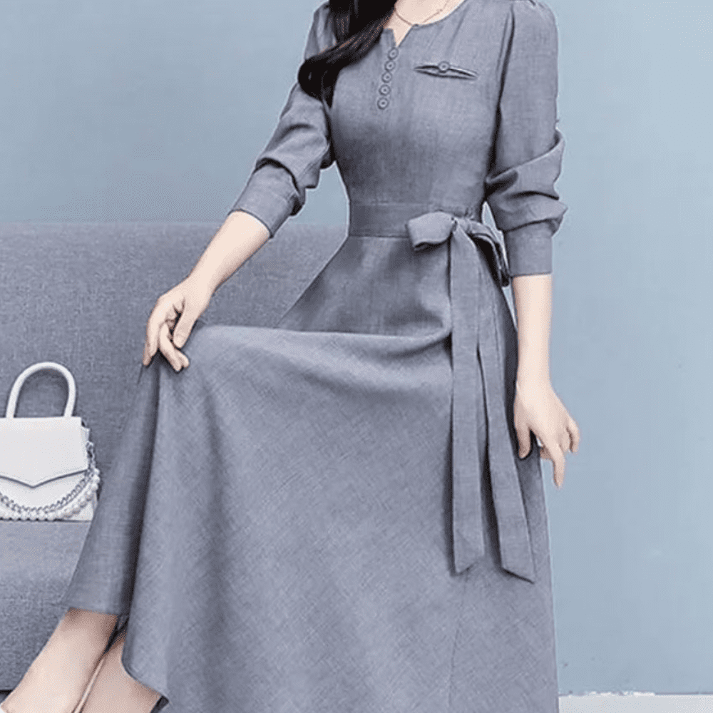 a woman sitting on a couch wearing a gray dress